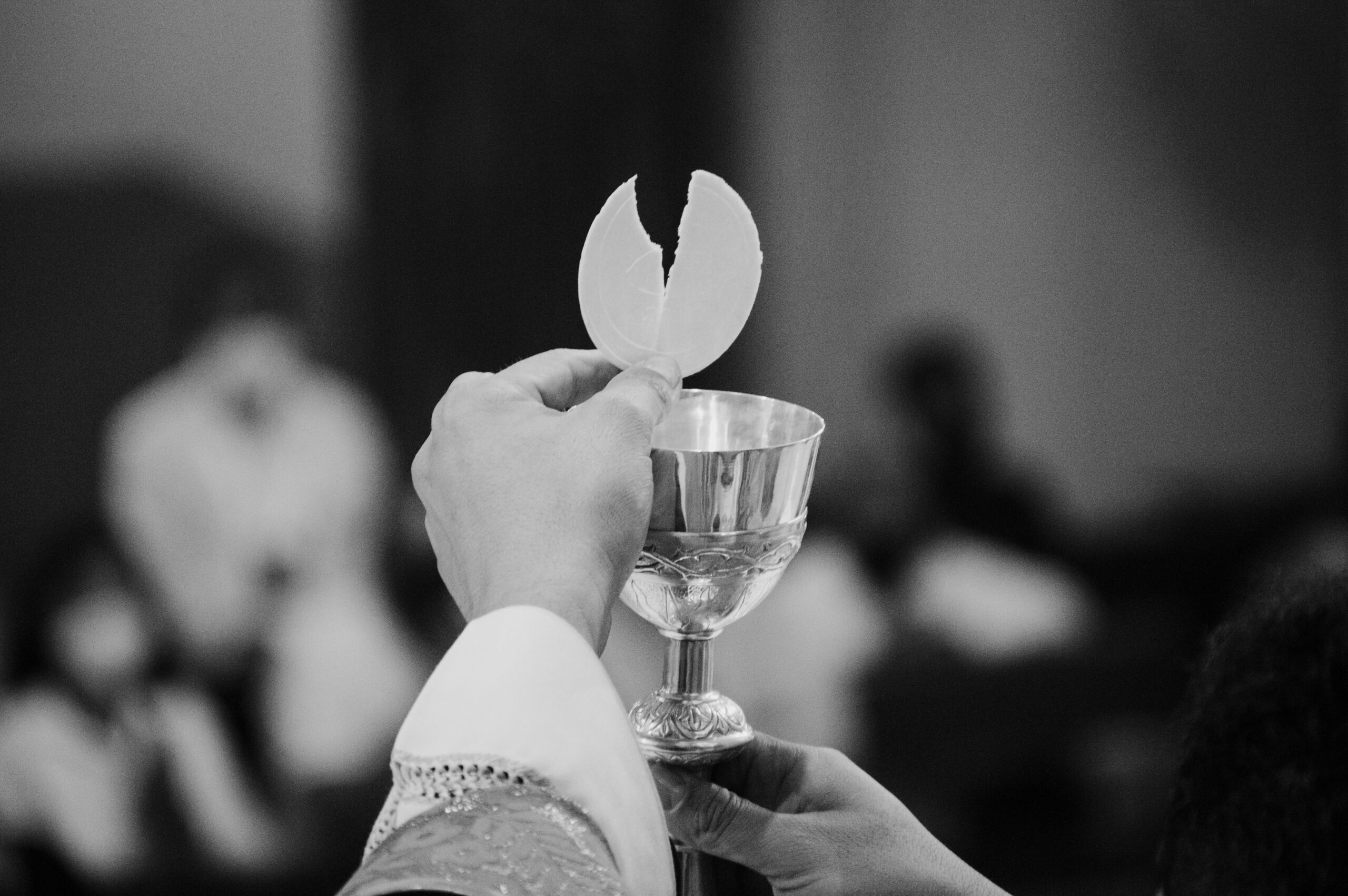 Close-up of a communion wafer held by a priest in a religious ceremony.
